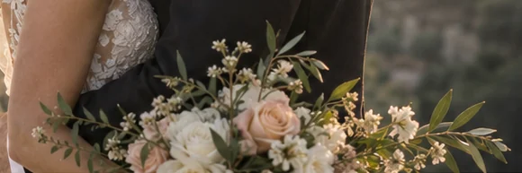 A bride's bouquet of peach roses, white flowers and olive leaves